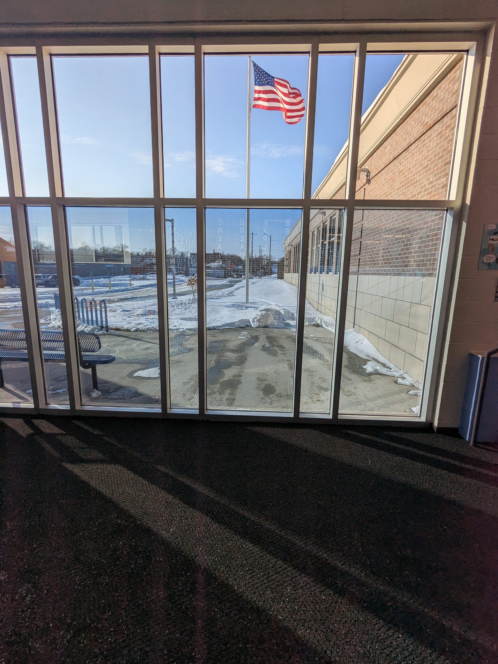 Entrance glass wall seen from inside with a flag outside