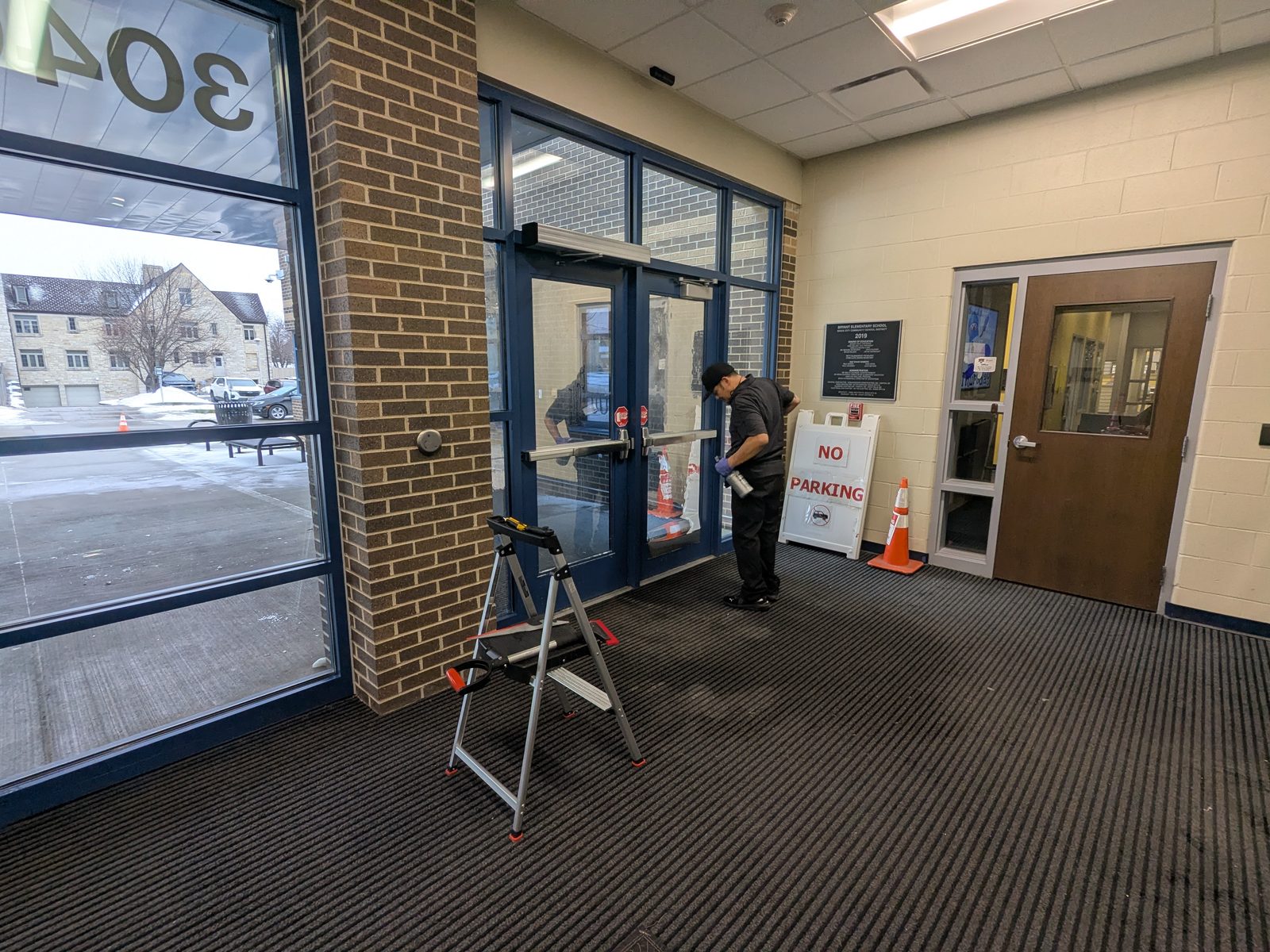 Installer on a step stool applying film to entry glass