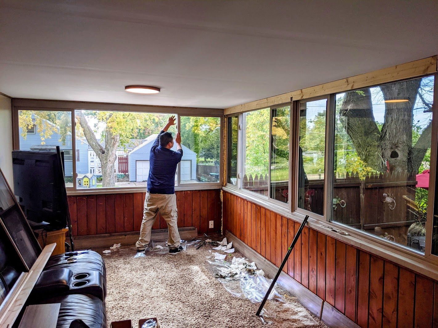 Installer applying film in a sunroom with many windows